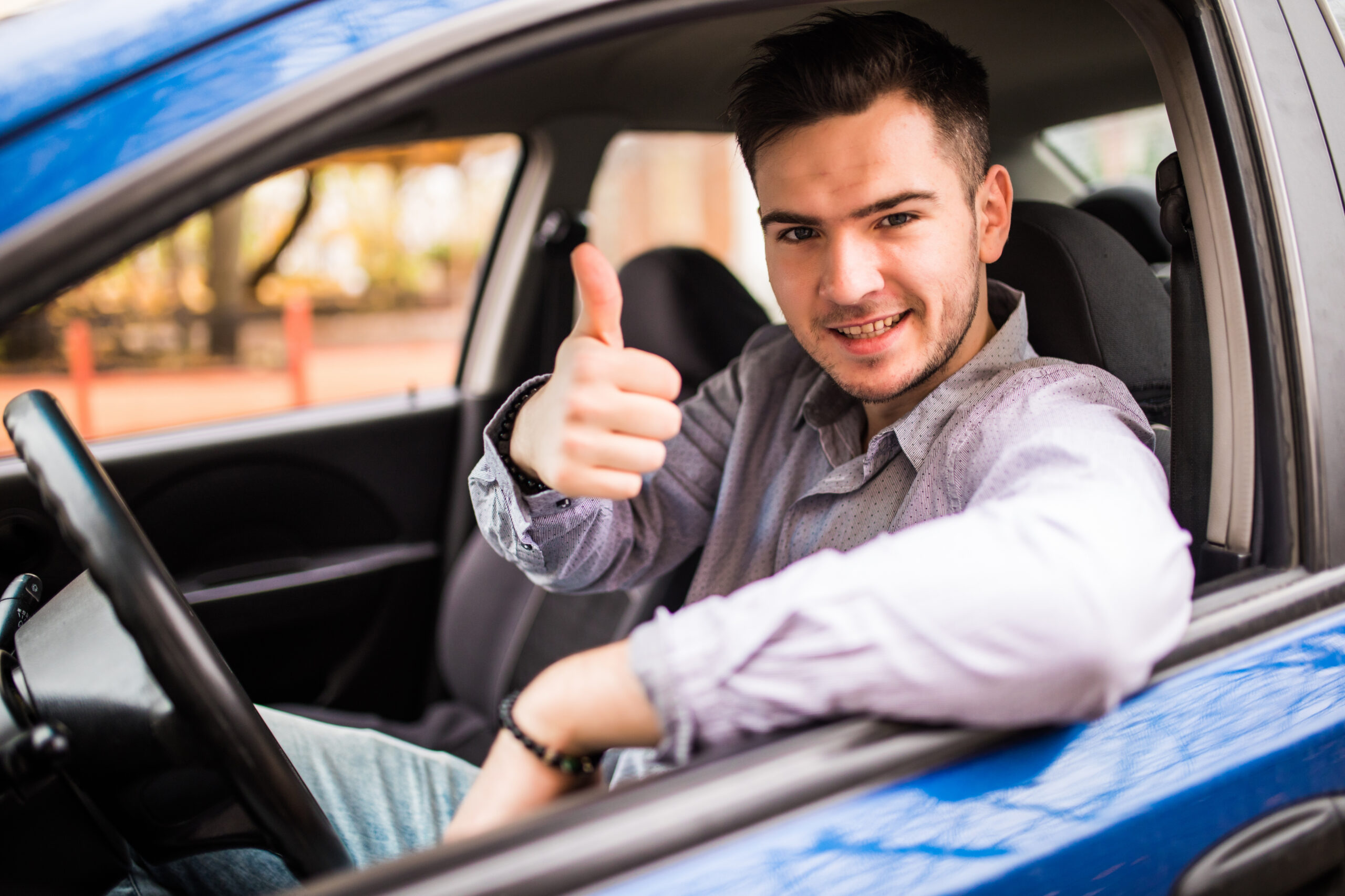 happy smiling man sitting inside car showing thumbs up. handsome